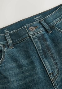 Ceinture de jeans en denim avec bouton, passants de ceinture et étiquette de taille imprimée "34R" ainsi que "Slim Fit, Narrow, Tapered, High" à l'intérieur de la ceinture.