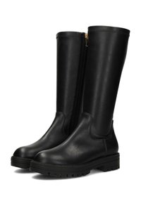 Par de botas de cuero negras hasta la rodilla con cremallera lateral y suelas gruesas tipo lug, en un ángulo que muestra los detalles del frente y el lado interior.