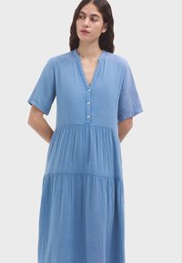 Himmelblaues, knielanges Kleid mit kurzen Ärmeln, einem geknöpften V-Ausschnitt und einem gestuften Rockdesign. Hergestellt aus strukturiertem Stoff.