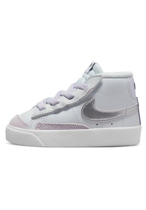 Baskets blanches mi-hautes avec lacets lavande, embout en daim, semelle blanche texturée et logo Nike en métal argenté sur le côté.