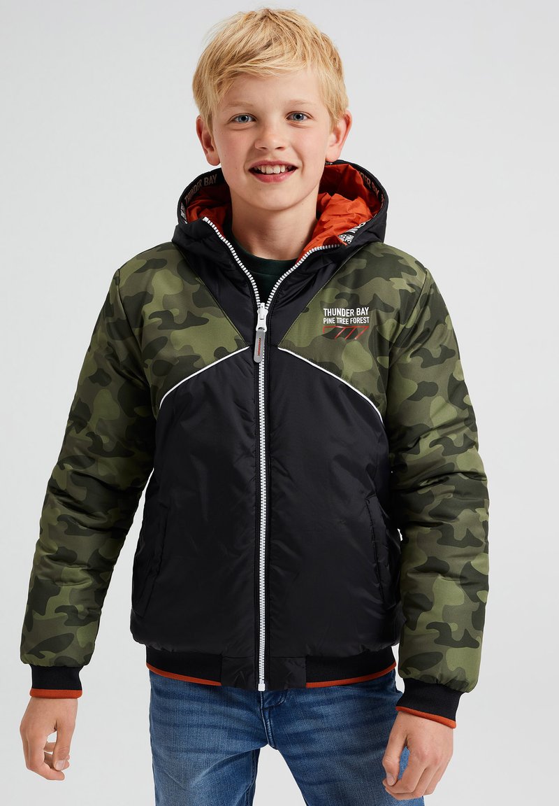 Mustavihreä camomalli puhvijakku punaisella vuorilla, valkoisilla yksityiskohdilla ja etuvetoketjulla. Varustettu hupulla ja joustavilla hihoilla.