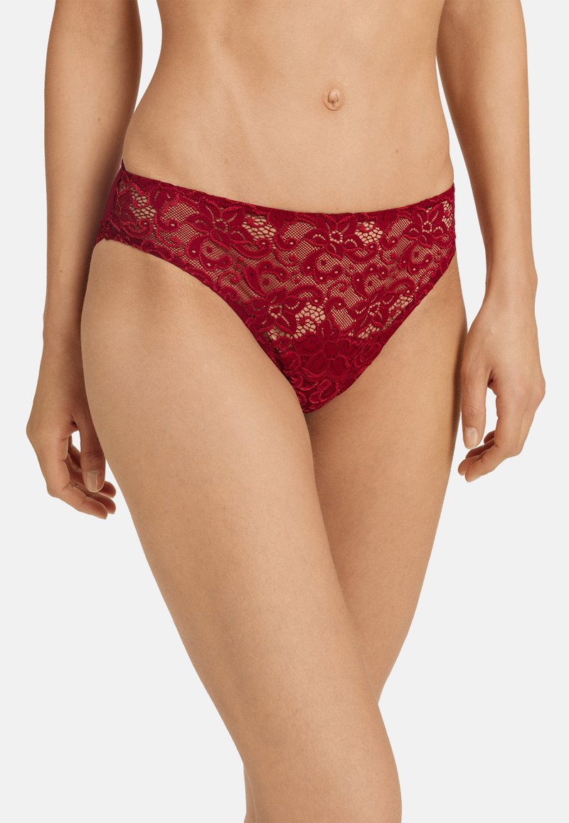 Slip bikini rosso in pizzo con motivo floreale, vita elastica e texture semitrasparente. Vestibilità sagomata con copertura moderata.