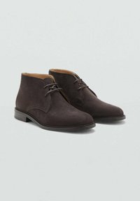 Bottines en suède gris foncé avec un bout arrondi, fermeture à lacets, et un intérieur en cuir lisse avec un petit talon empilé.