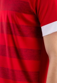 Rotes Sportshirt mit horizontalen Streifen in verschiedenen Rottönen, kurzen weißen Ärmeln und einer leichten Stoffstruktur.