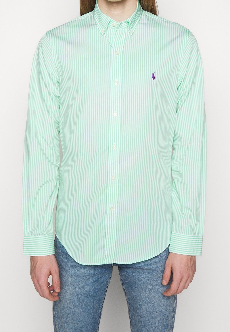 Light green long-sleeve shirt with white vertical stripes, button-down collar, front buttons, and a small purple logo on the chest.