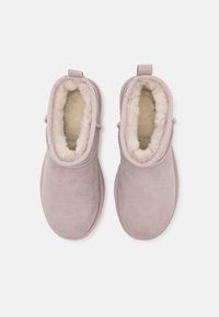 Botas de tobillo de ante rosa claro con un suave forro de pelo, puntera redondeada y una pequeña lengüeta en la parte posterior para ponérselas fácilmente.