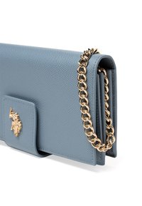 Bolso de mano de cuero azul claro con superficie texturizada, correa de cadena dorada y tapa frontal con un logo dorado. Diseño compacto y rectangular.