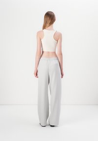 Light gray wide-leg trousers with an elastic waistband, paired with a beige cropped tank top. Smooth fabric and minimal design.