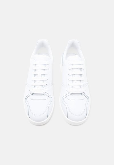 Ζευγάρι λευκά χαμηλά αθλητικά παπούτσια με κορδόνια, σε θέα από πάνω πάνω σε απλό ανοιχτό φόντο.