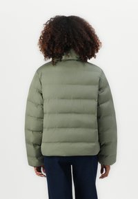 Olijfgroene pufferjack met hoge kraag, gequilt ontwerp en een relaxte pasvorm. Heeft lange mouwen en een gladde, matte textuur.