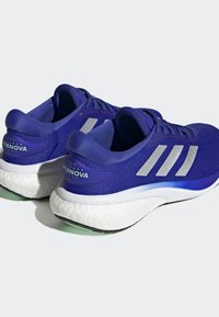 Purple athletic shoes with a breathable mesh upper, silver accents, a white cushioned midsole, and green outsole detailing.
