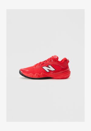 Sneaker atletica rossa con suola nera, lacci e un logo "N" bianco di lato, mostrata su uno sfondo grigio chiaro uniforme.