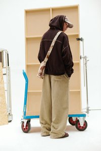 Barna kapucnis pulóver kontrasztos varrással, bézs színű kordbársony nadrág és műszőrméből készült keresztpántos táska. Puha anyag és laza szabás.