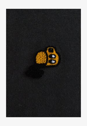 Zwarte stof met fijne verticale ribbels heeft een geborduurde gele en zwarte cartoonachtige bijontwerp, dat textuur en detail laat zien.