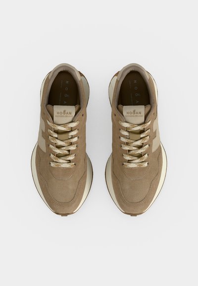Paire de baskets beiges en daim et mesh avec des lacets à motifs et des semelles blanches épaisses vues de dessus sur un fond uni.