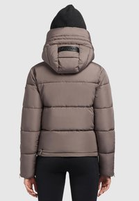 Puffer jas in lichtbruin met een afneembare capuchon, voorzien van een doorgestikte textuur, elastische manchetten en een logo-accent op de achterkant.