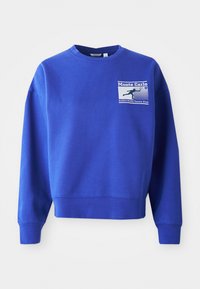 Μπλέ φούτερ με στρογγυλή λαιμόκοψη και μακριά μανίκια. Διαθέτει γραφικό στο μπροστινό μέρος του στήθους με τις λέξεις "Monte Carlo" και "Björk Borg Tennis Club."