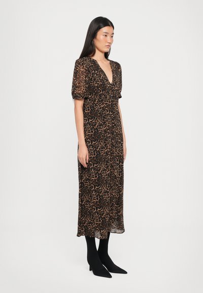 Svart midi-kjole med brun abstrakt mønster, med dyp V-hals og korte pufferm, båret med svarte spisse hæler.
