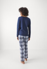 Marinblå långärmad topp i kombination med ljusblå och vit rutiga pyjamasbyxor. Byxorna har en lös passform och en mjuk bomullstextur.