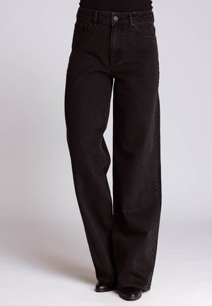 Black high-waist wide-leg jeans worn with black top and black shoes, shown from waist to feet against plain background.
