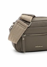 Sac à bandoulière texturé gris avec une sangle tressée et une poche zippée, présentant un accent en métal avec logo sur le devant.