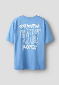 Blå bomullströja med korta ärmar, med vit text: "SKATEBOARDING KONSTEN ATT FALLA 'MED GRACE'" på baksidan.