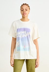 Crèmekleurig t-shirt van katoen, met een grafische print in blauw en paars, die een schelp en surfplanken afbeeldt. Losse pasvorm.