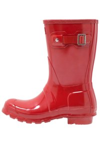 Červená lesklá gumová deštníková bota s boční sponou a vroubkovanou podrážkou, umístěná na bílém pozadí.