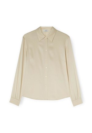 Blouse beige à manches longues, boutonnée, avec col pointu et poignets froncés, présentée à plat sur un fond blanc.