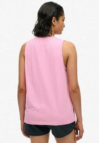 Jasnoróżowy bezrękawnik o okrągłym dekolcie i miękkiej fakturze, charakteryzujący się luźnym fasonem i małą metką po boku.