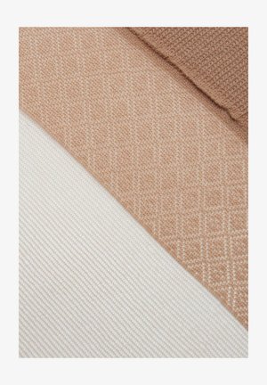 Zbliżenie beżowych i kremowych próbek tkanin o wyraźnych tkanych fakturach i wzorach, ułożonych diagonalnie.