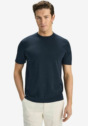 Navy blue short-sleeve t-shirt made of smooth fabric with a classic crew neckline and relaxed fit, paired with light-colored trousers.