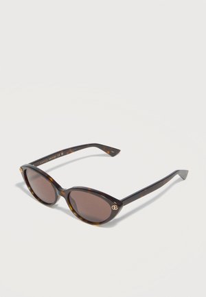 Cat-eye tortoiseshell sunglasses with dark lenses and gold Gucci logo on the upper corners of the frames.