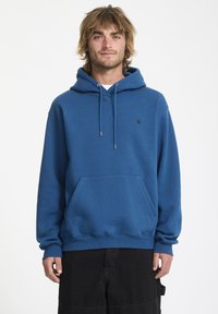Blauwe hoodie van zachte stof, met een voorzak, trekkoordcapuchon en een klein zwart logo op de borst. Lange mouwen en een relaxte pasvorm.