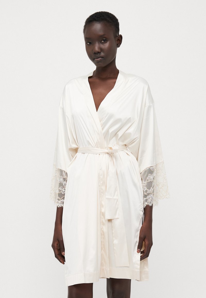 Accappatoio di seta di un avorio chiaro con maniche bordate in pizzo, dotato di una vita con cintura e una finitura in raso morbido. Design elegante e vestibilità ampia.