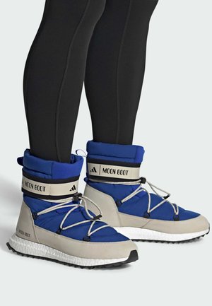 Niebieskie i szare buty Moon Boot z wyściełanym kołnierzem, białymi sznurówkami, teksturowanym materiałem i gumową podeszwą. Oferują markowy pasek i charakterystyczny kształt.