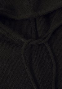 Felpa nera lavorata a maglia con un motivo a coste testurizzato. Presenta un cordino al collo per la regolabilità. Colore ricco e profondo.