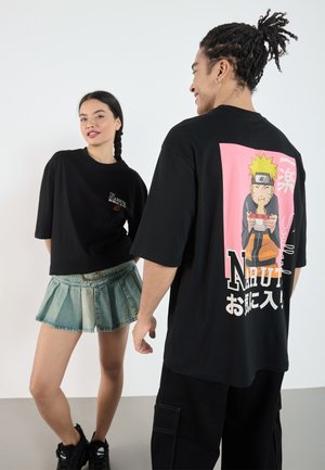 Black oversized t-shirt featuring a colorful Naruto graphic on the back. Text is displayed in both Japanese and English.