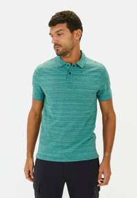 Turkusowa koszulka polo z krótkim rękawem o teksturowanym wzorze pasków, z kołnierzykiem i zapięciem na trzy guziki. Luźny krój.