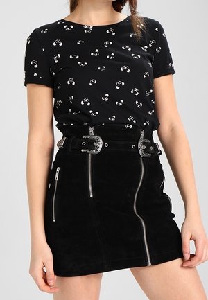 Black short-sleeve shirt with white abstract print paired with high-waist black suede skirt featuring silver zippers and double buckle belt.