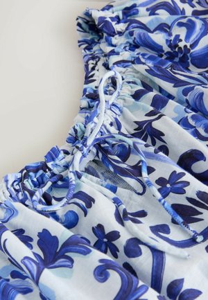 Blumenmusterstück in Blautönen, mit geraffter Textur, Kordelzugdetails und Stoff mit wirbelnden Mustern.