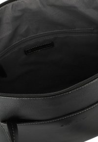 Sac en cuir noir avec une texture lisse et une fermeture éclair, doté d'un intérieur noir spacieux et d'une petite poche zippée à l'intérieur.