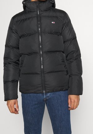 Veste matelassée noire avec fermeture éclair à l'avant, col montant, et deux poches latérales. Fabriquée dans un matériau lisse et brillant avec un design matelassé.