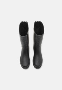 Bottes en caoutchouc noir avec un dessus texturé présentant un motif subtil, des ouvertures larges et un design lisse et profilé.