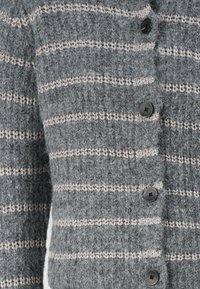 Γκρι πλεκτή ζακέτα με οριζόντιες μπεζ ρίγες, διακοσμημένη με υφασματική υφή, μαύρα κουμπιά και κομμένα μανίκια.