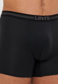 Fekete Levi's boxer alsónadrág puha anyagból, szürke csíkos derékpánttal és varrás nélküli dizájnnal, kiemelve a kényelmet és a megfelelő illeszkedést.