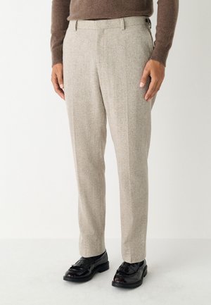 Pantalones beige confeccionados a medida con tela texturizada, que cuentan con un frente plano, bolsillos laterales y cierre de dos botones en la cintura.