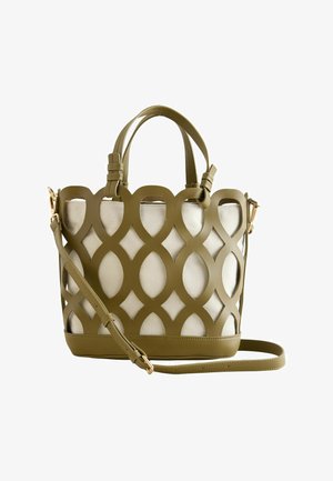 Olivengrøn håndtaske med cirkulært udskåret mønster overlay på beige stof, med to håndtag og en justerbar skulderrem.