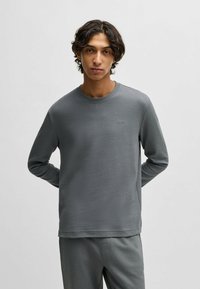 Grijze lange mouwen shirt met wafeltextuur, ronde hals en logo-detail. Strak ontwerp met zachte, gestructureerde stof.