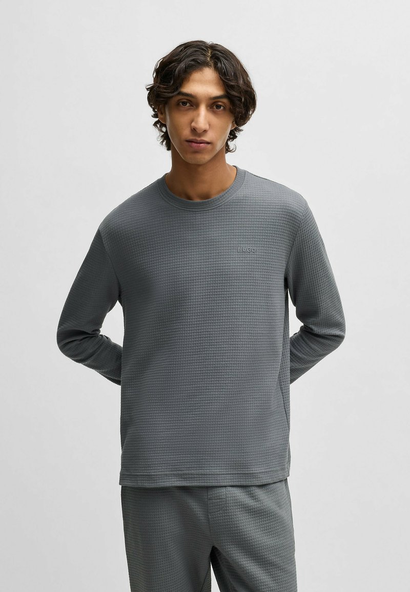 Grijze lange mouwen shirt met wafeltextuur, ronde hals en logo-detail. Strak ontwerp met zachte, gestructureerde stof.
